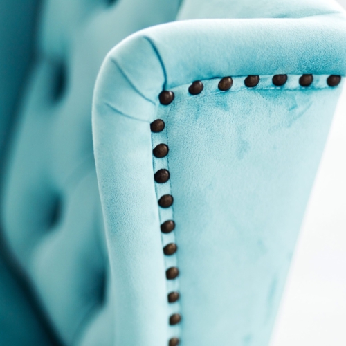 Close-up shot of a blue upholstered chair featuring intricate rivet detailing. Close-up shot of a blue upholstered chair featuring intricate rivet detailing.